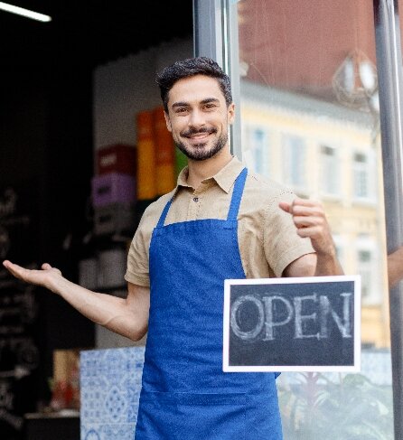 man standing in an apron with an open sign